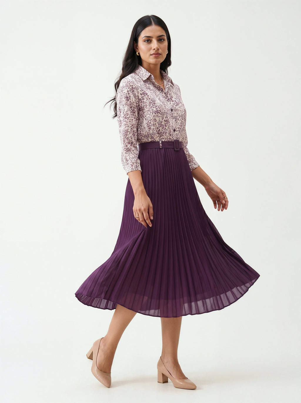 Woman wearing a floral blouse and purple pleated skirt on a white background