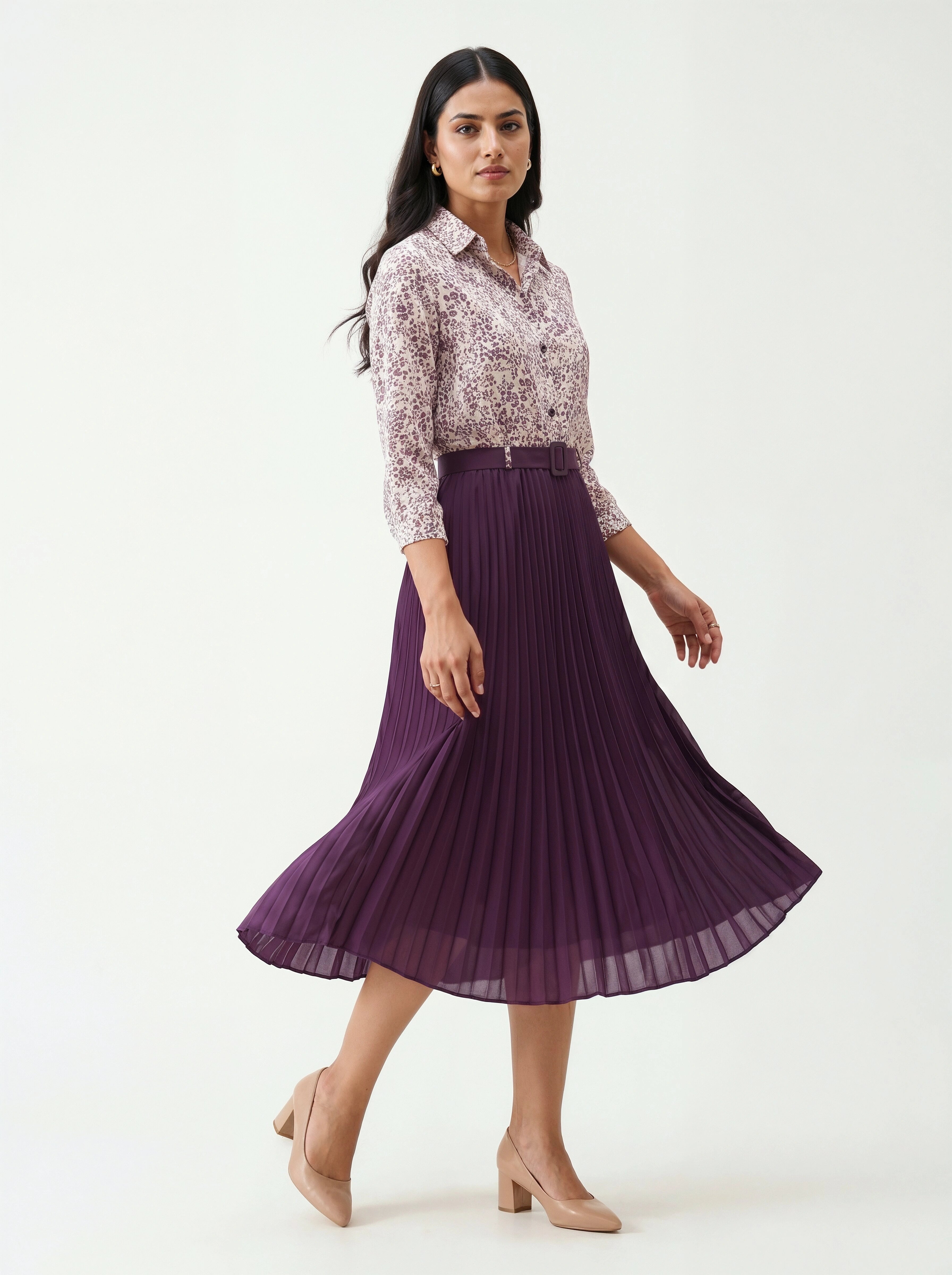 Woman wearing a floral blouse and purple pleated skirt on a white background