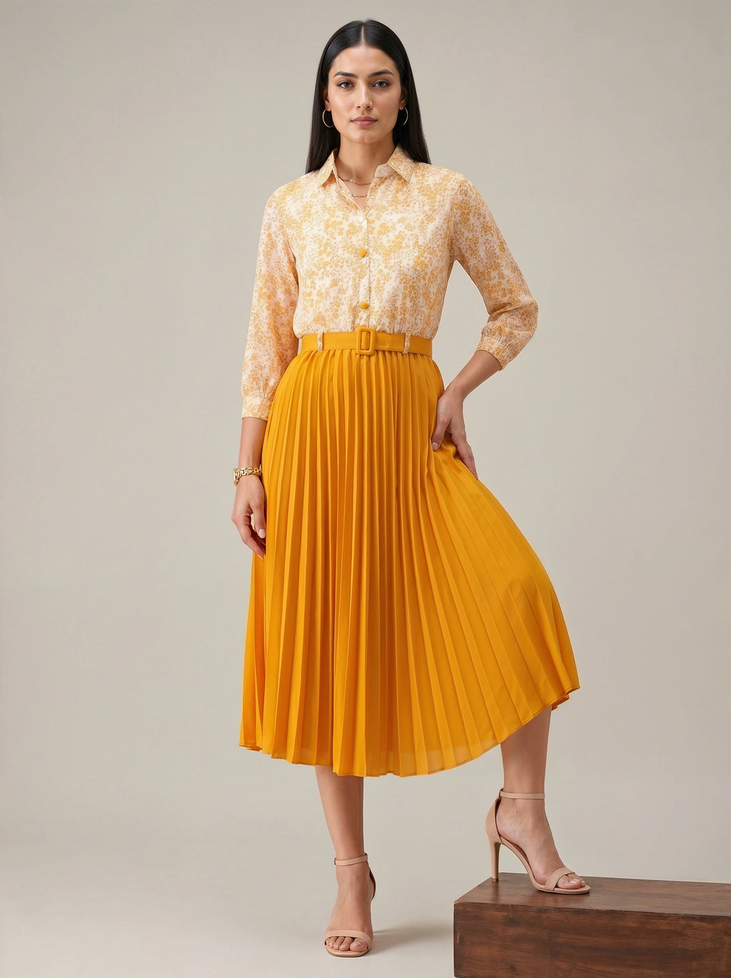 Woman wearing a yellow lace blouse and pleated skirt on a neutral background