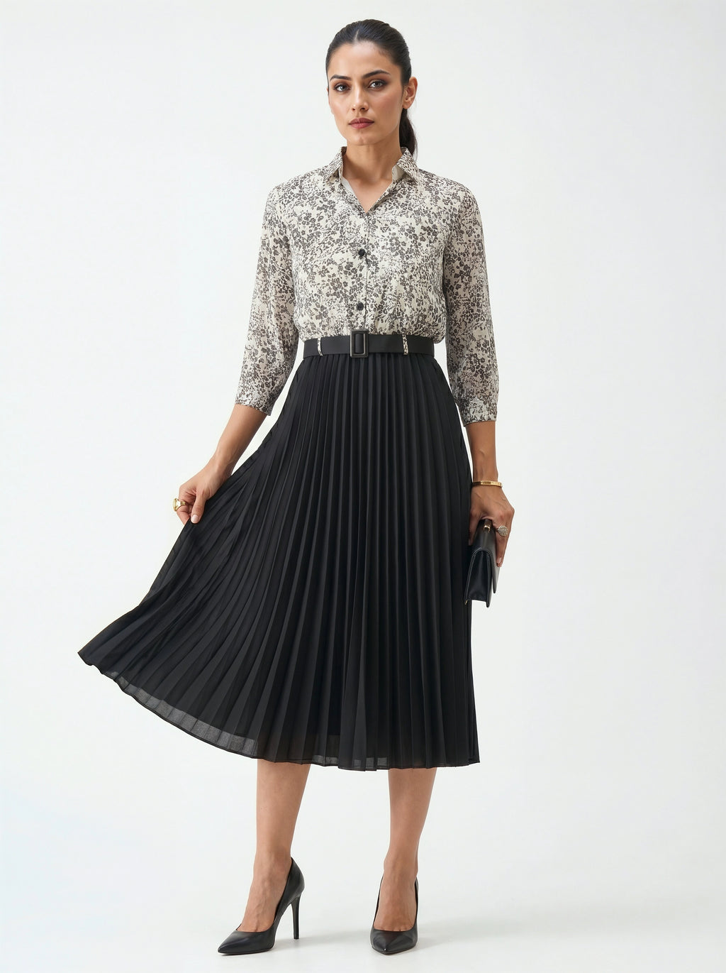 Woman wearing a floral top and black pleated skirt on a white background