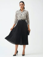 Woman wearing a floral top and black pleated skirt on a white background