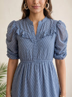 Woman wearing a gray dress with ruffled details in an elegant interior setting