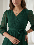 Woman wearing a green dress with a white curtain background