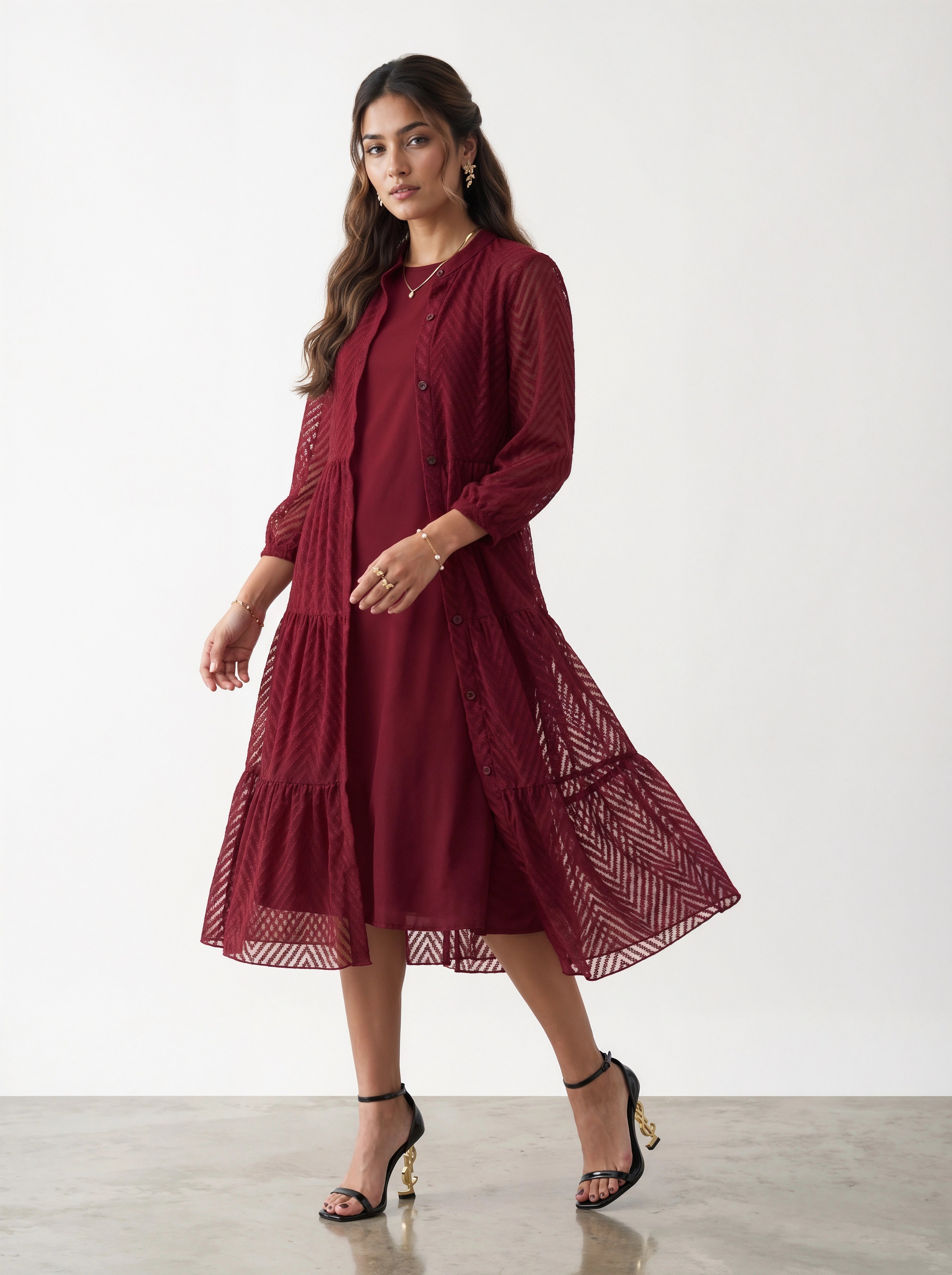 Woman wearing a burgundy dress with sheer sleeves against a white background