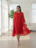 Woman in a red dress standing in a bright living room.