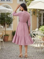 Woman in a pink dress standing outdoors on a patio