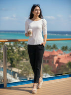 Woman standing on a balcony overlooking a scenic view with coffee in hand