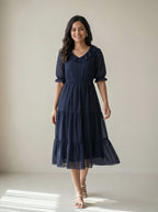 Woman wearing a navy blue dress with a plain background