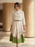 Woman wearing a white blouse with floral skirt in an indoor setting