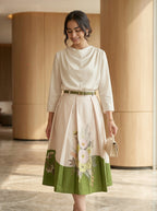 Woman wearing a white blouse with floral skirt in an indoor setting