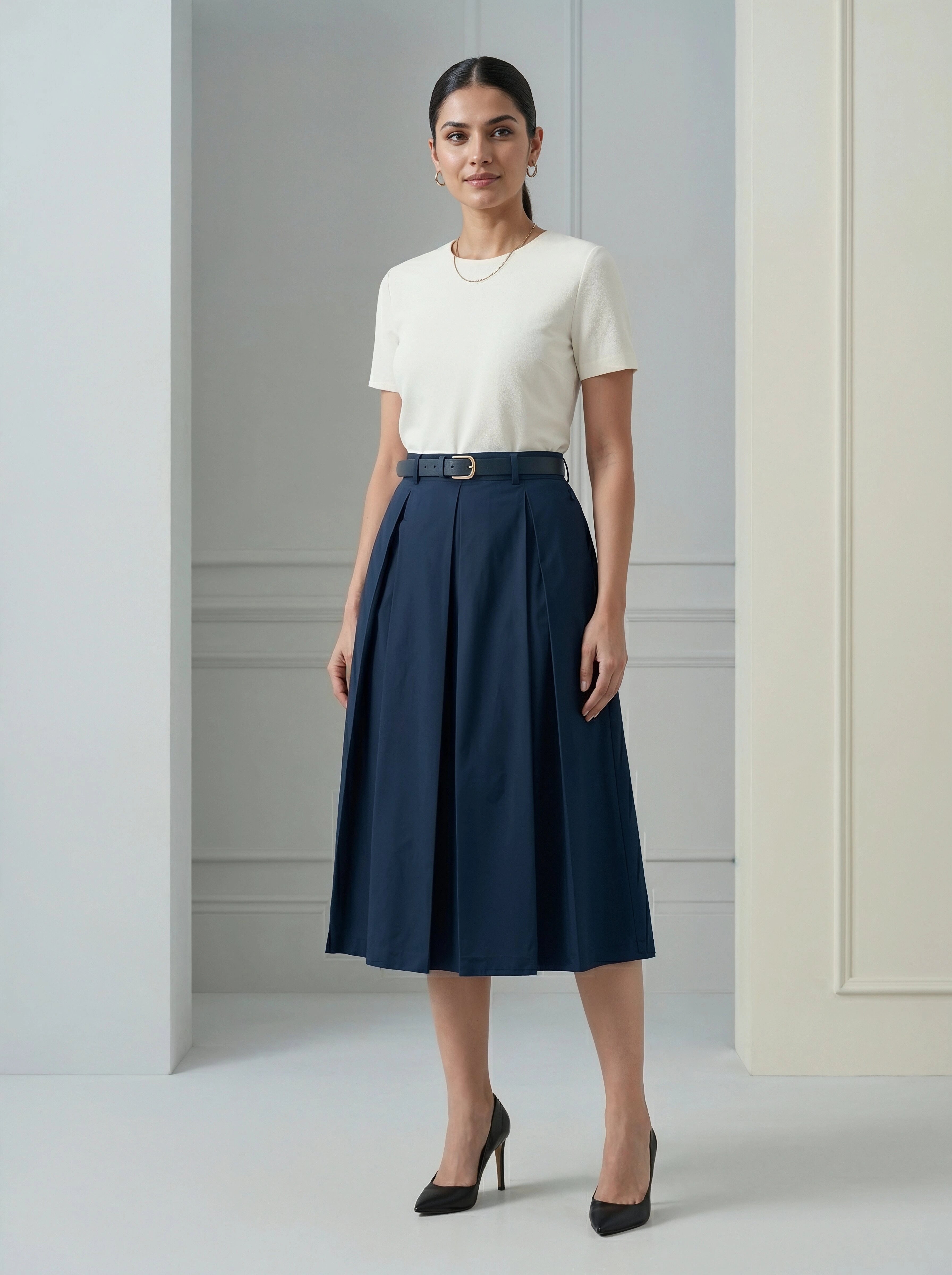 Woman wearing a white top and navy skirt in a minimalistic setting