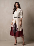 Woman wearing a white blouse with a floral design on a maroon skirt against a plain background