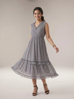 Woman wearing a gray patterned dress on a plain background