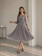 Woman wearing a gray patterned dress in an indoor setting