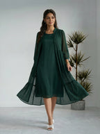 Woman wearing a green dress with a matching cardigan in a minimalistic setting.