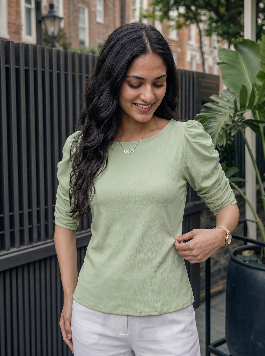 Woman wearing a light green top with puffed sleeves outdoors.