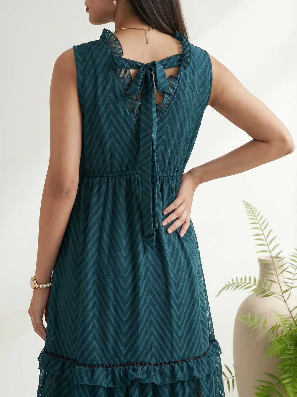 Woman wearing a teal dress with a geometric pattern, standing against a neutral background.