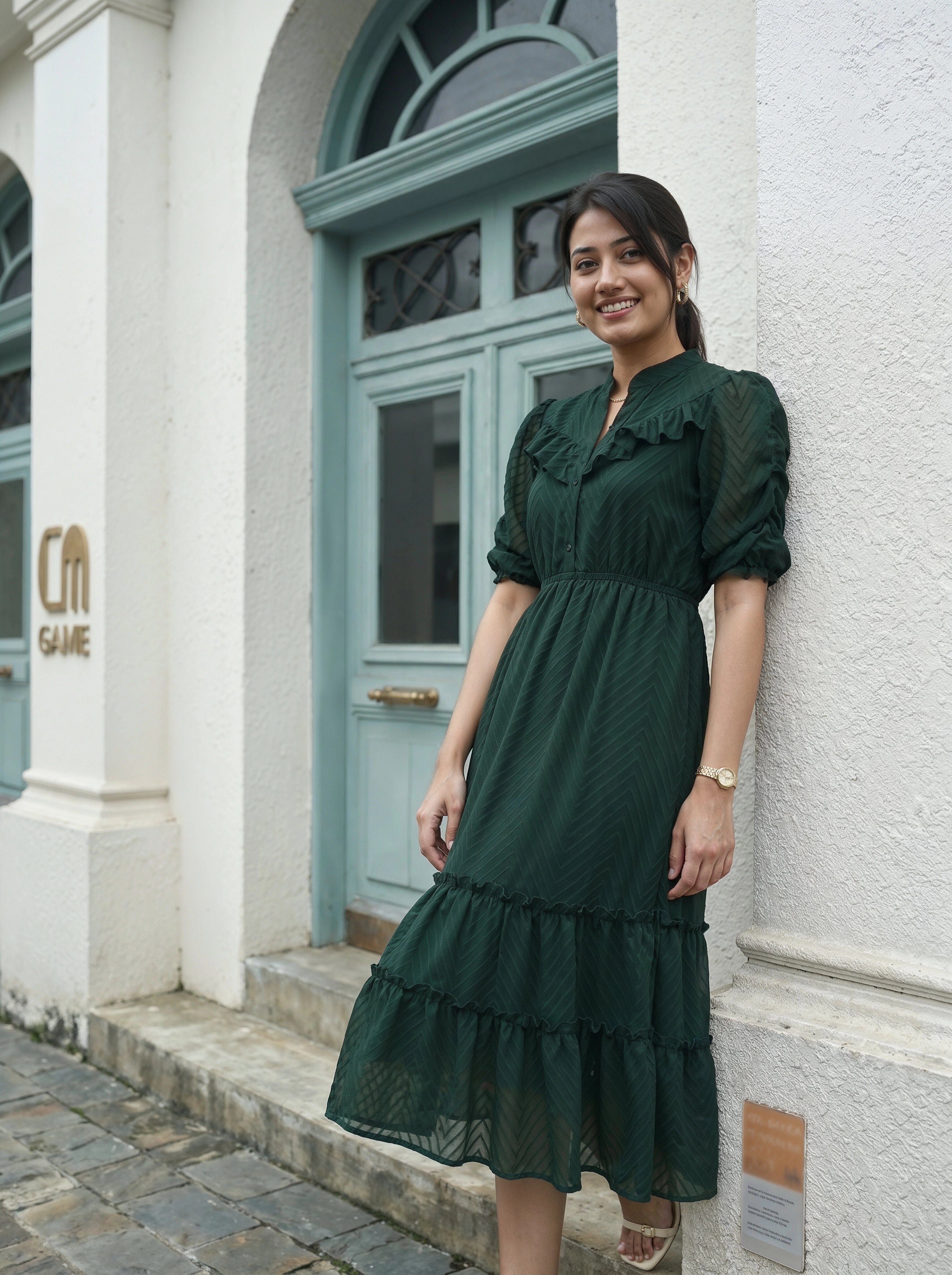 Woman in a green dress standing in front of a building with a blue door.