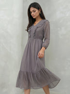 Woman wearing a gray dress against a plain background