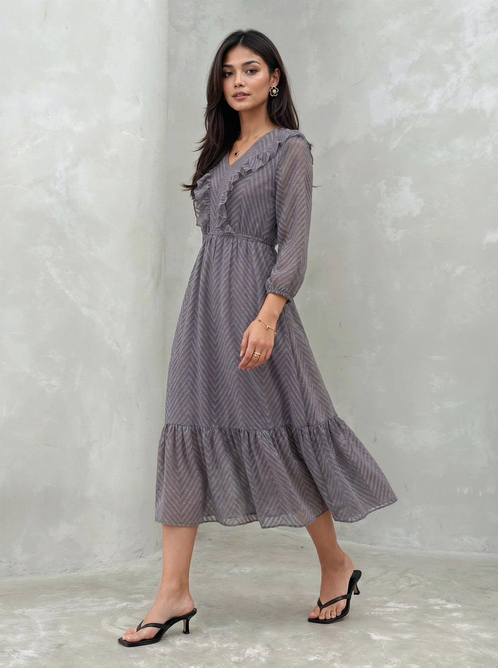 Woman wearing a long, patterned dress against a plain background