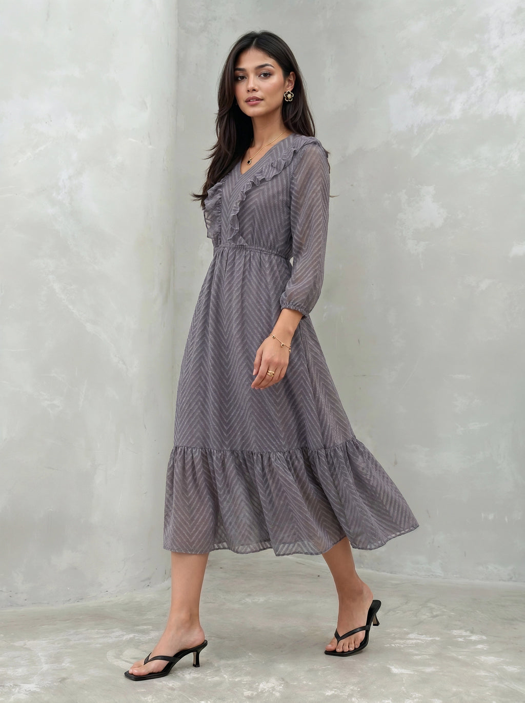 Woman wearing a long, patterned dress against a plain background