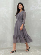 Woman wearing a long, patterned dress against a plain background