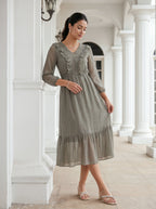 Woman wearing a gray dress standing in a bright, elegant interior setting.
