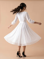 Woman wearing a white dress against a beige background