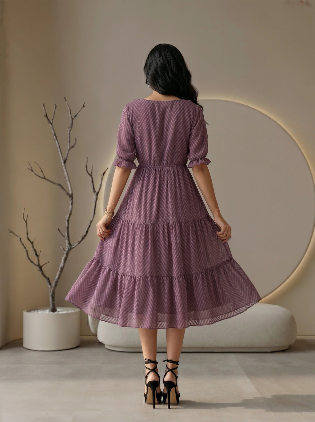Woman wearing a black dress standing in a modern living room.