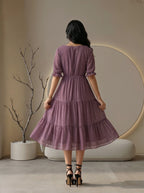 Woman wearing a black dress standing in a modern living room.