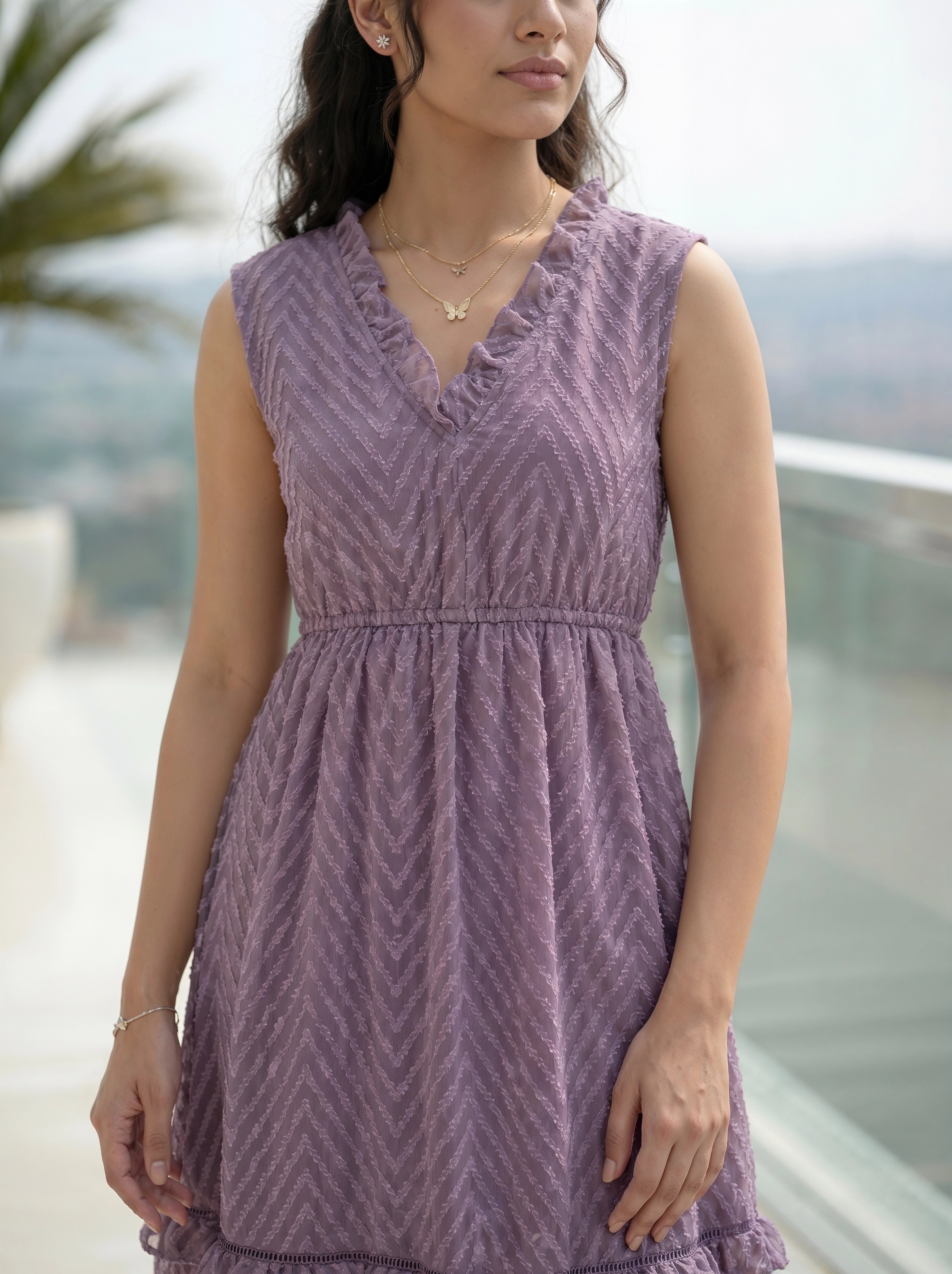 Woman wearing a purple patterned dress with a blurred outdoor background