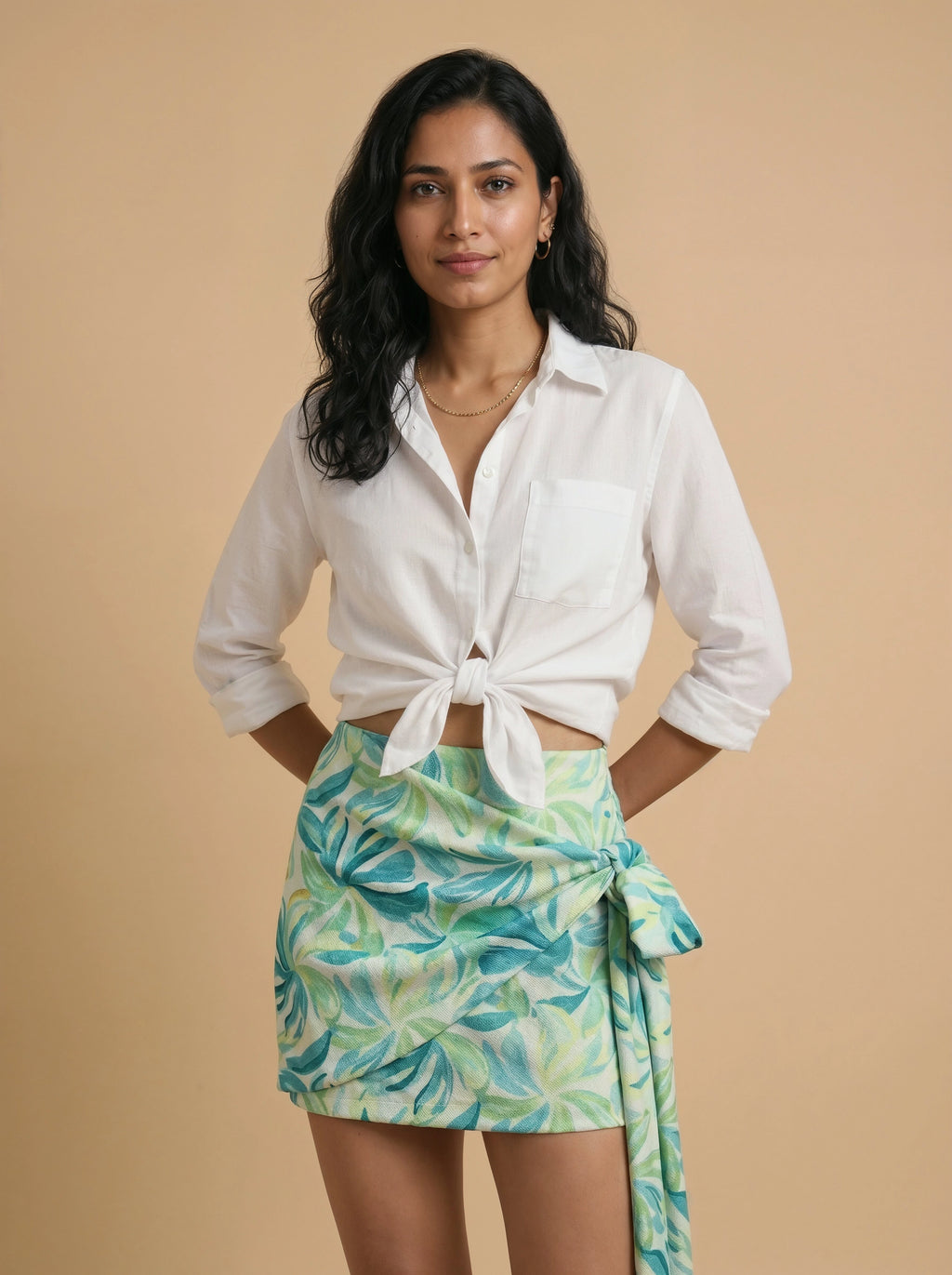 Woman wearing a white shirt and green leaf-patterned skirt against a beige background
