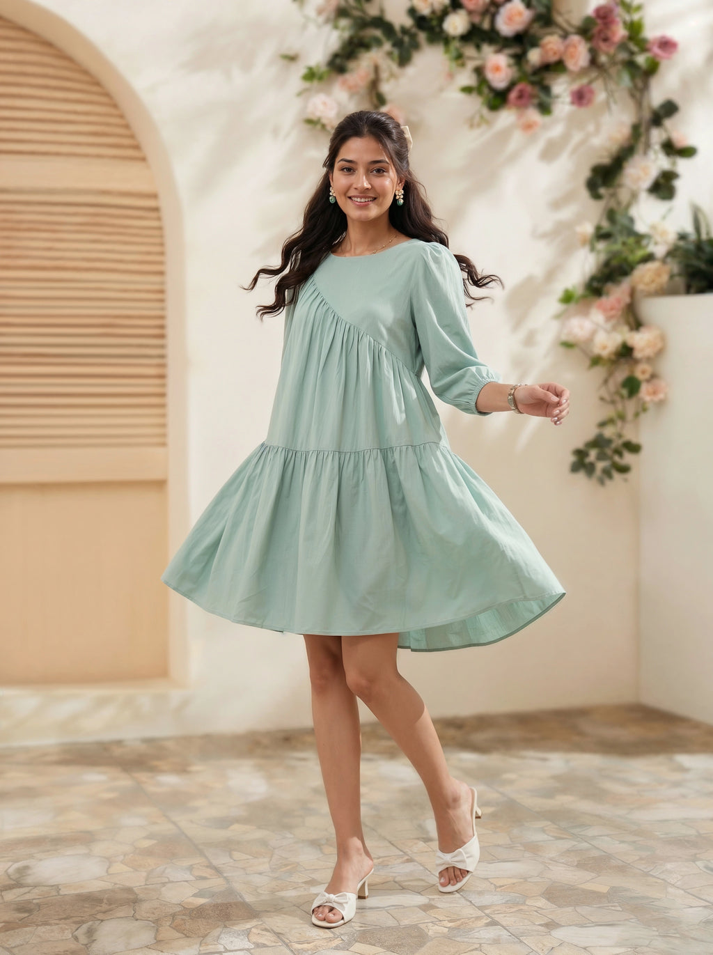 Woman in a light blue dress standing in a decorated indoor setting with flowers and arches.