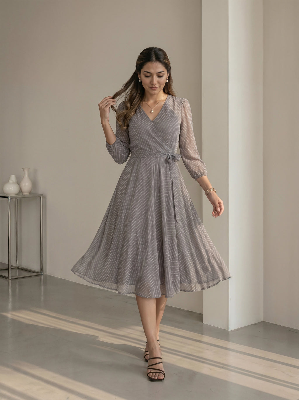Woman wearing a gray patterned dress in a minimalistic room.