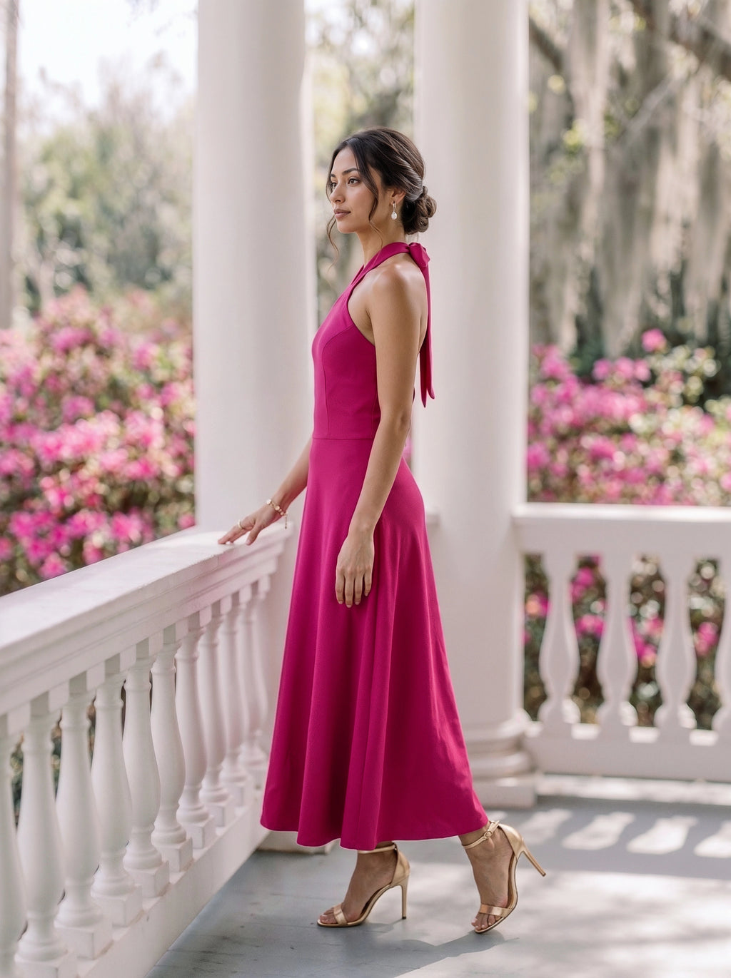 A woman modeling a light mint green tiered dress with three-quarter sleeves, standing in a warm, sunlit indoor setting with floral wall decor and stone flooring.