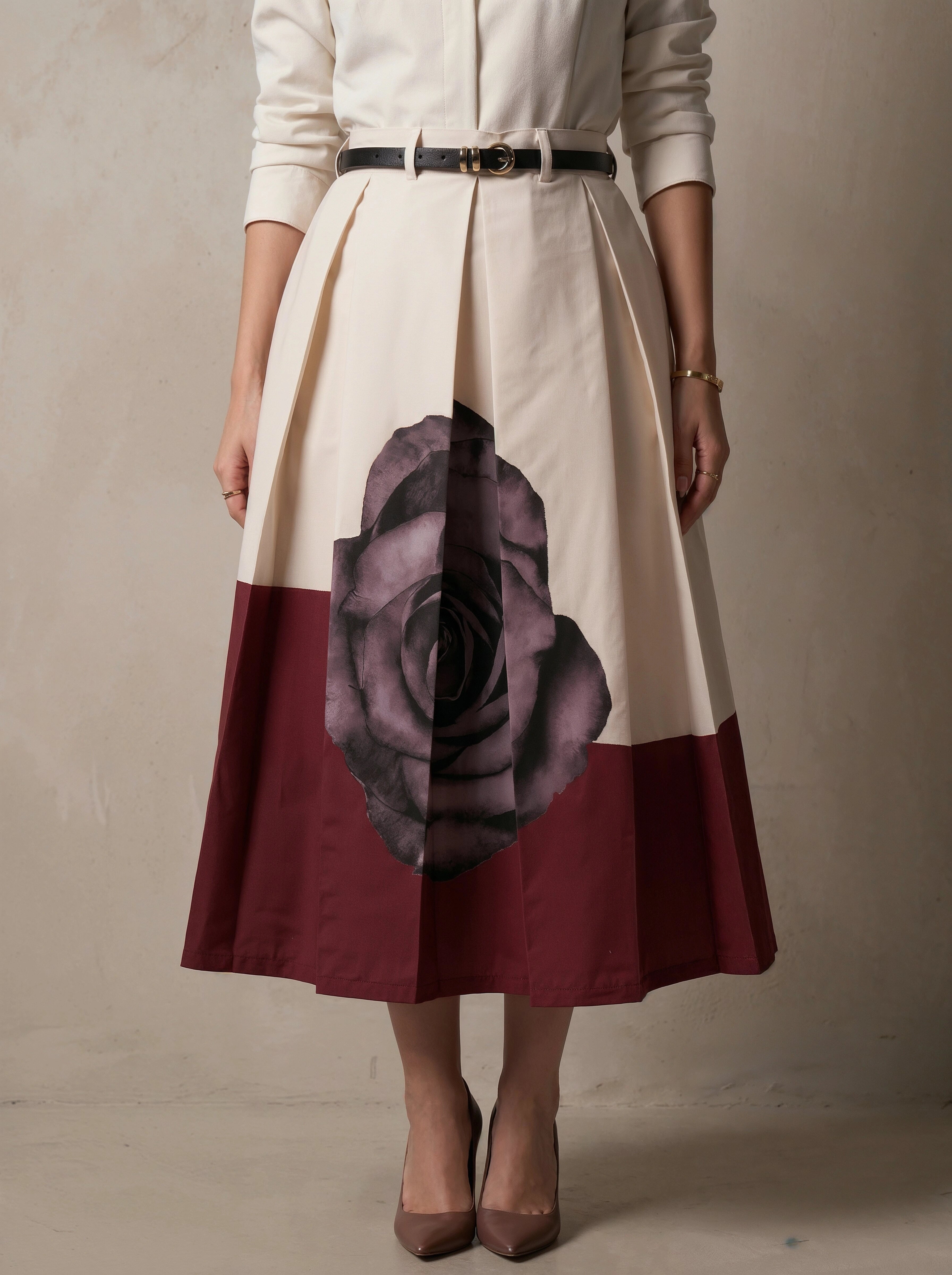 Person wearing a skirt with a large maroon rose design on a plain background