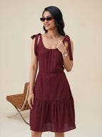 Woman wearing a burgundy dress with bow straps on a beige background