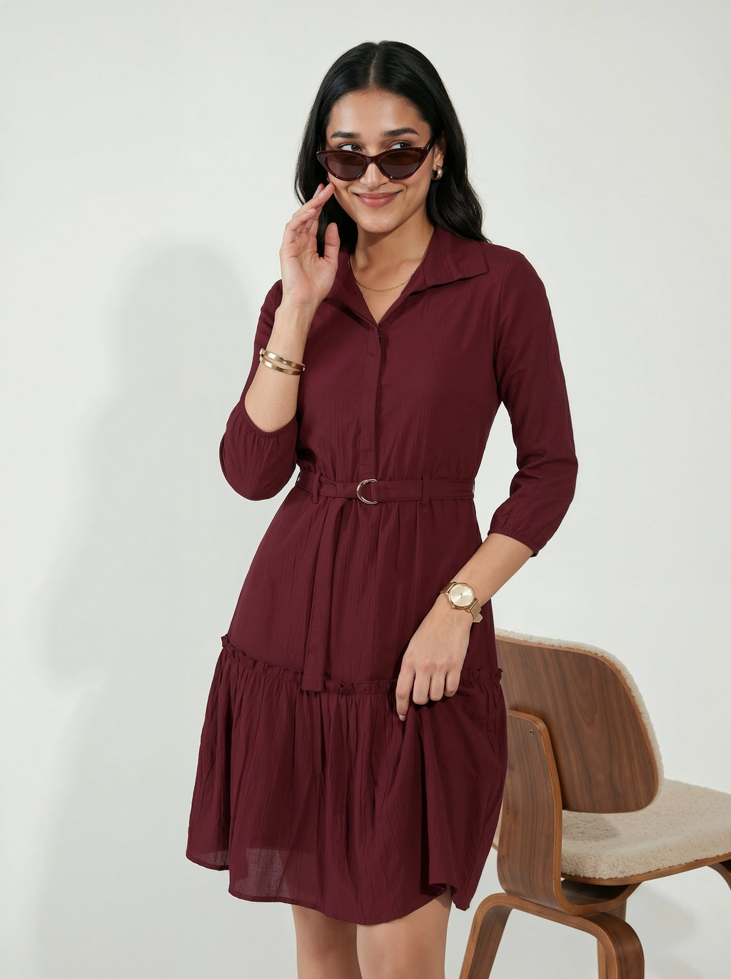 Woman in a burgundy dress talking on a phone with a white background