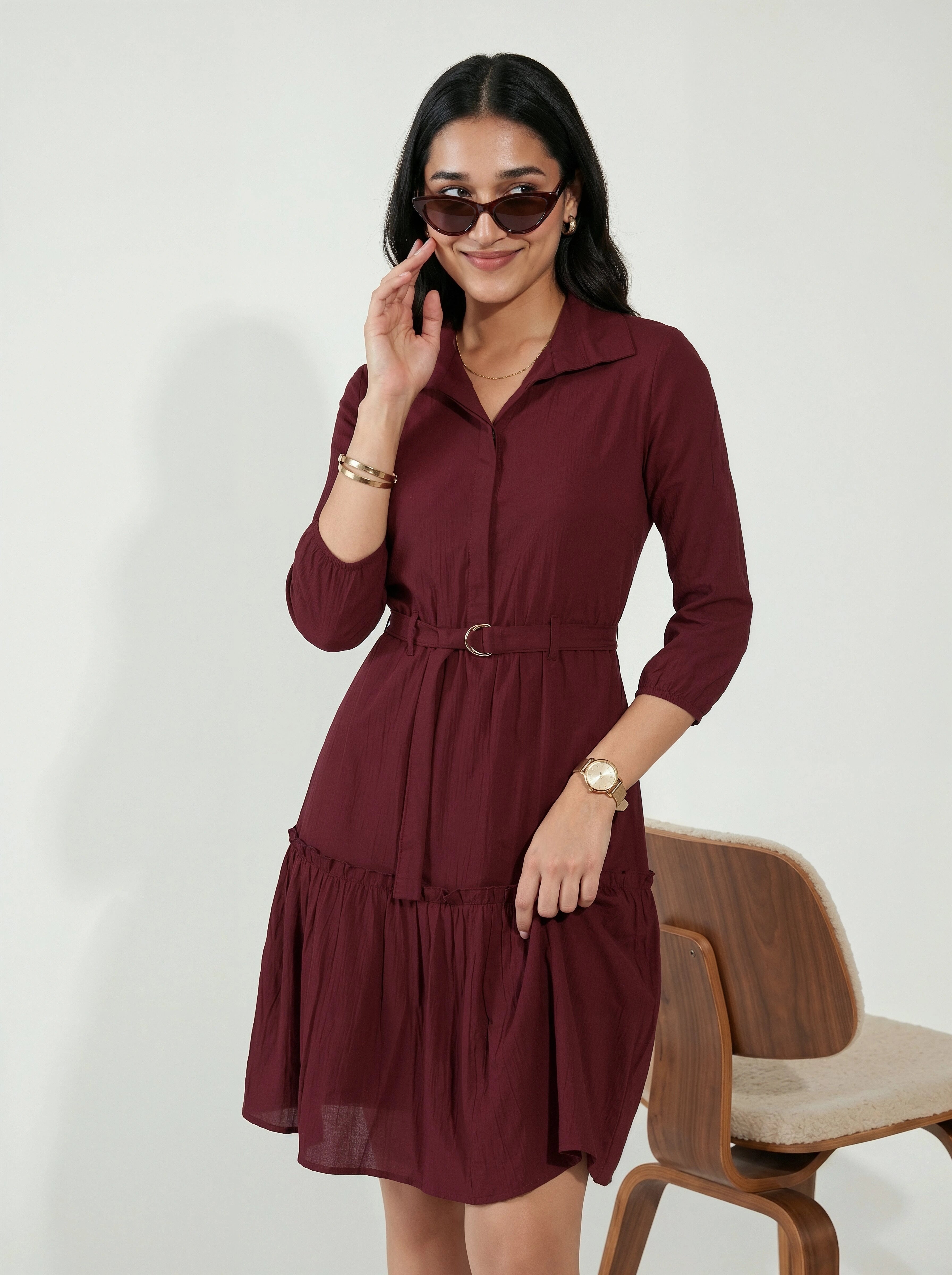 Woman in a burgundy dress talking on a phone with a white background