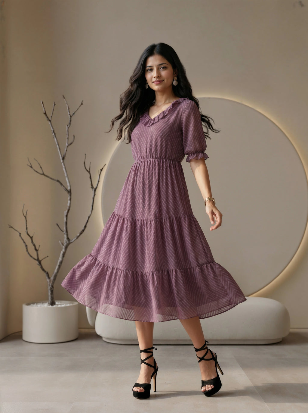 Woman wearing a mauve tiered dress with ruffled details in a modern living room setting