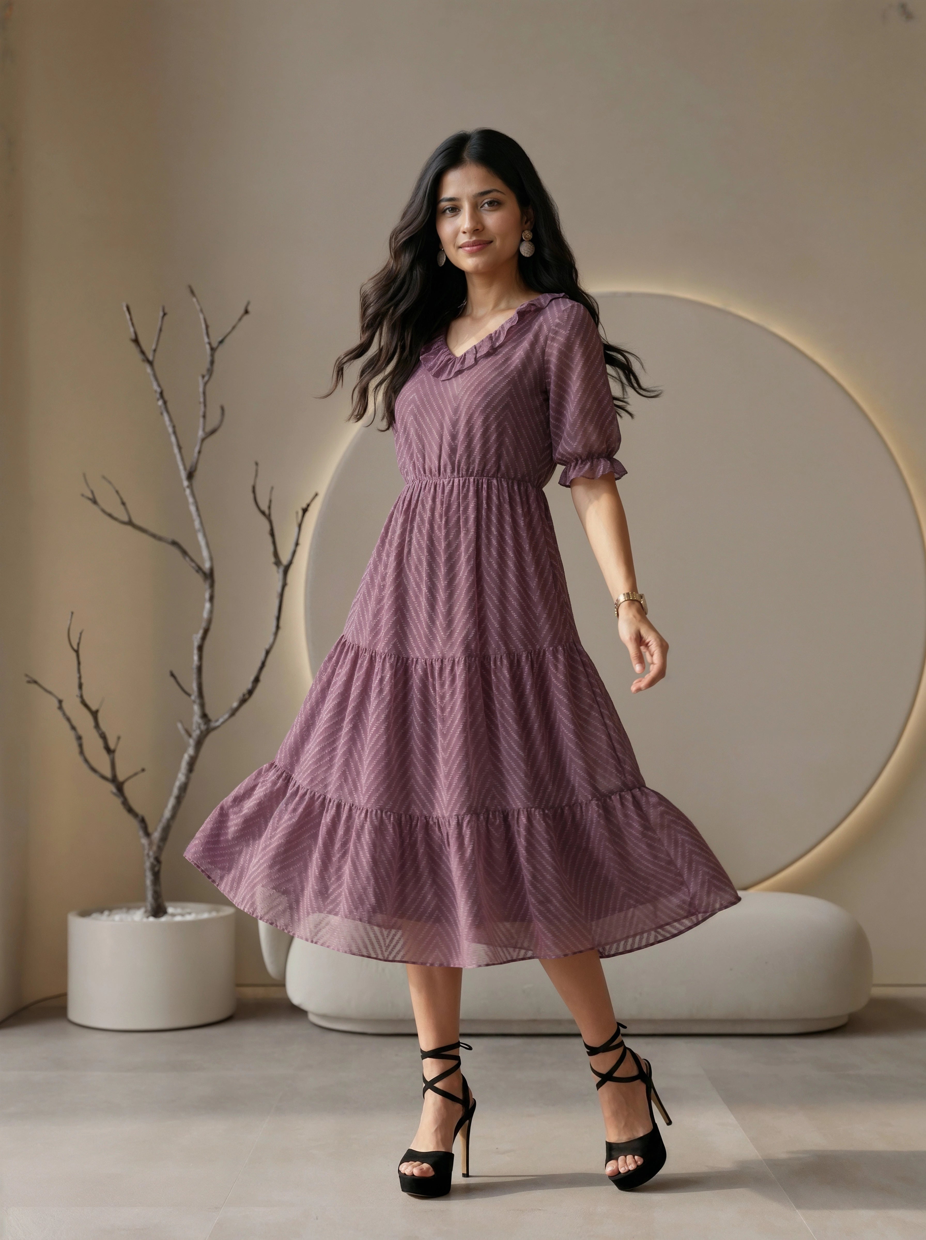 Woman wearing a mauve tiered dress with ruffled details in a modern living room setting