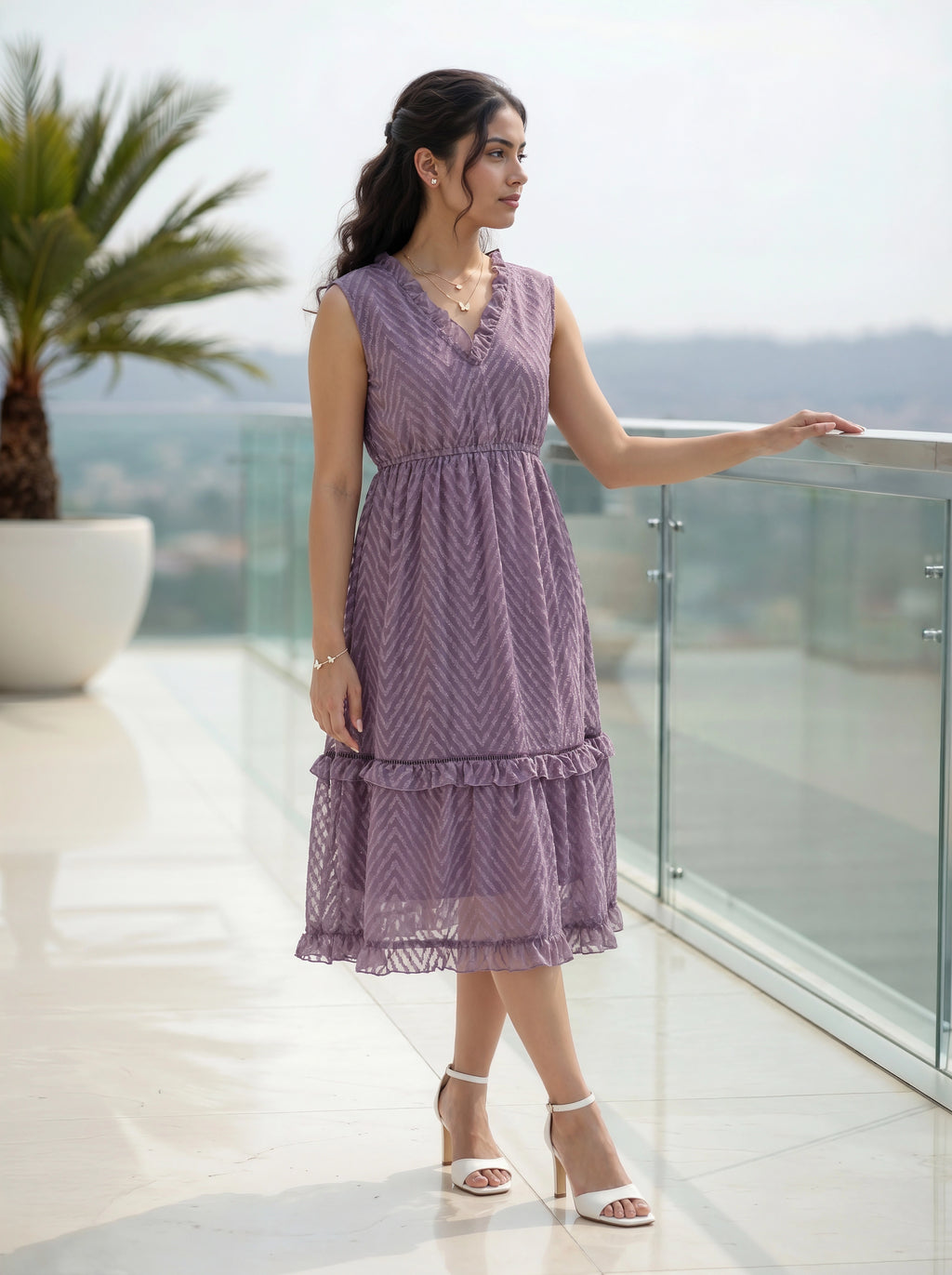Woman in a purple dress standing on a balcony with a scenic view.