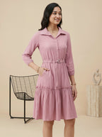 Woman wearing a pink dress standing against a beige background