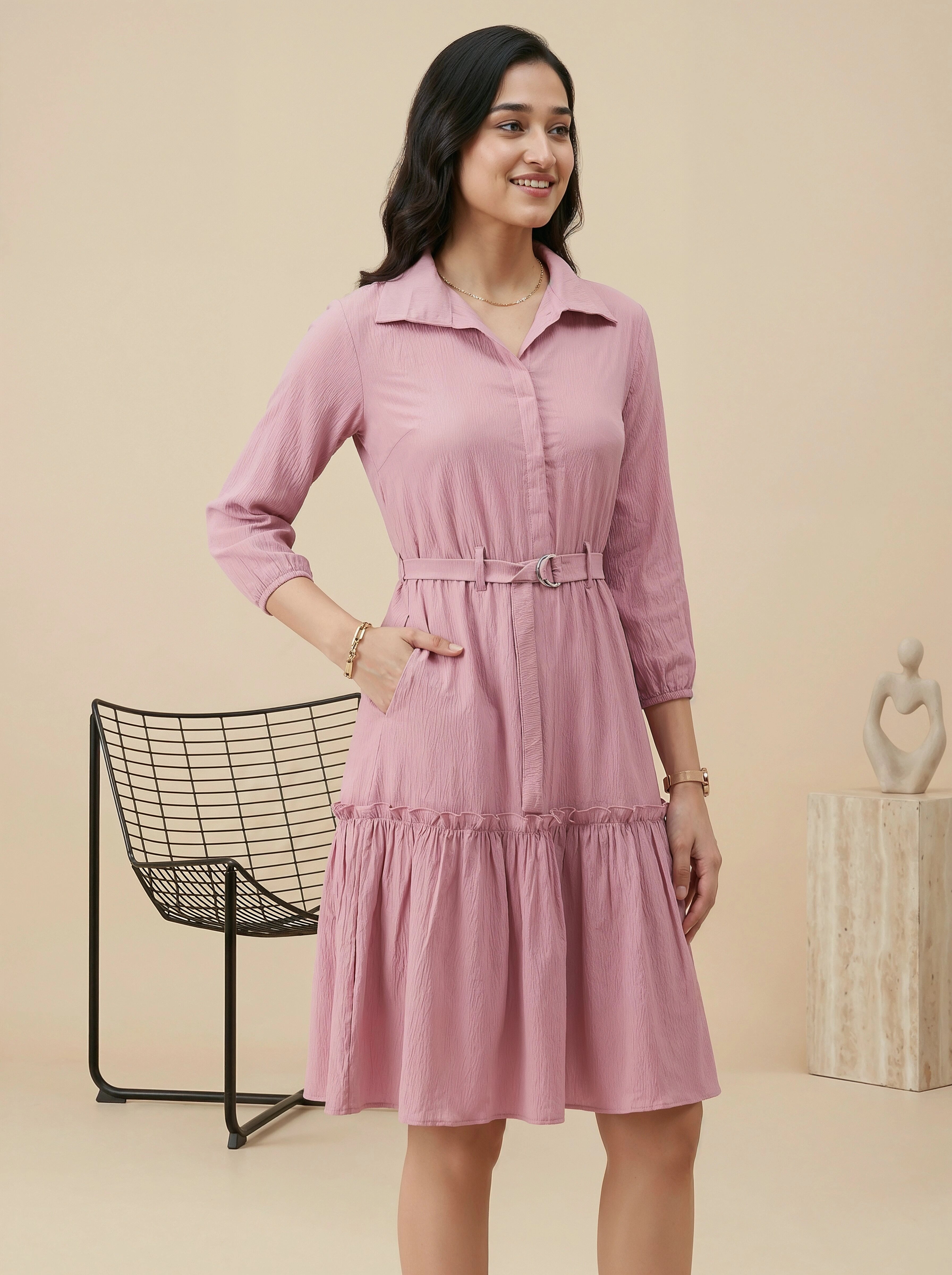 Woman wearing a pink dress standing against a beige background