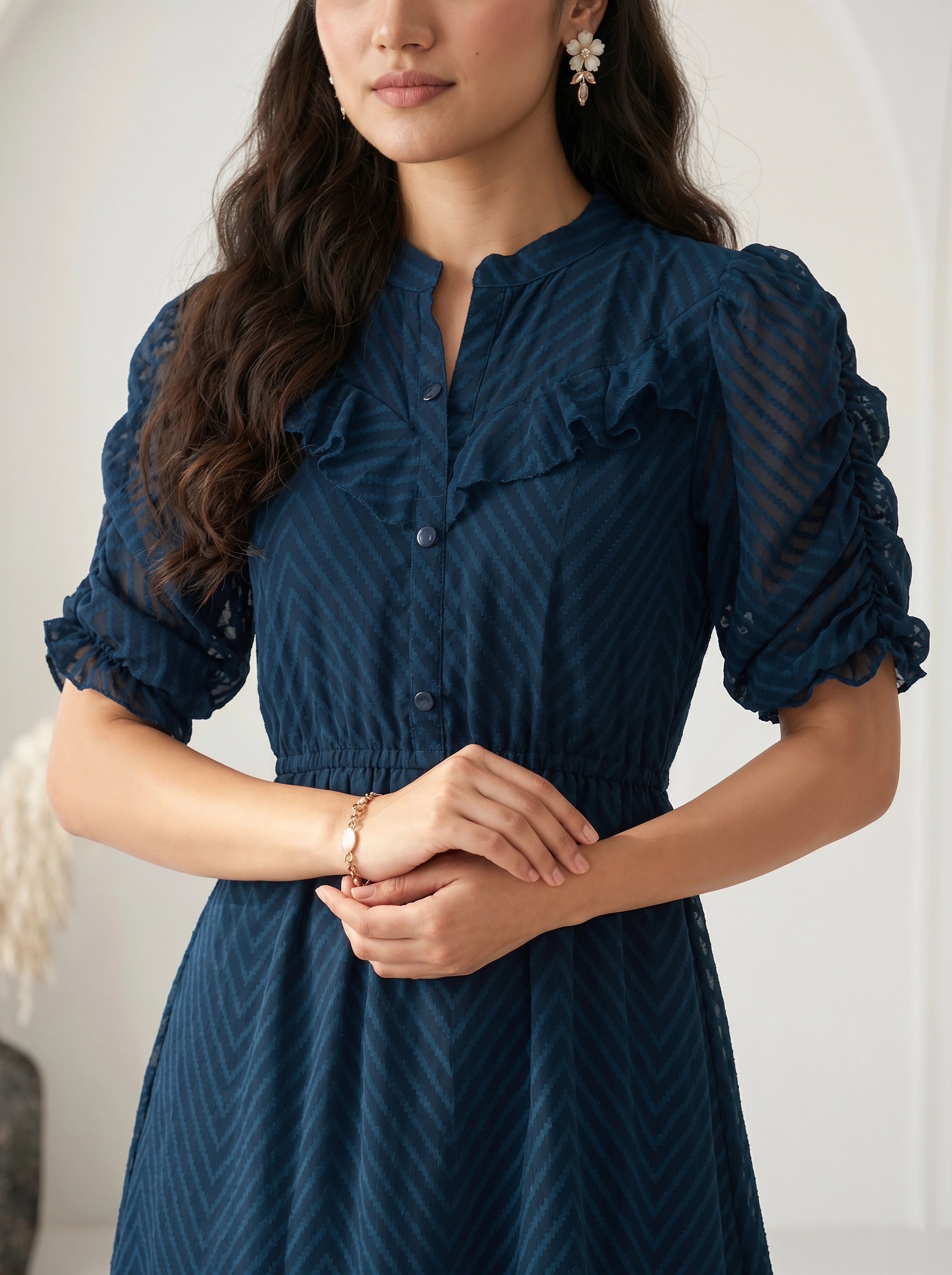 Woman wearing a gray dress with a subtle pattern against a plain background