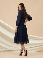 Woman wearing a navy blue lace dress against a beige background