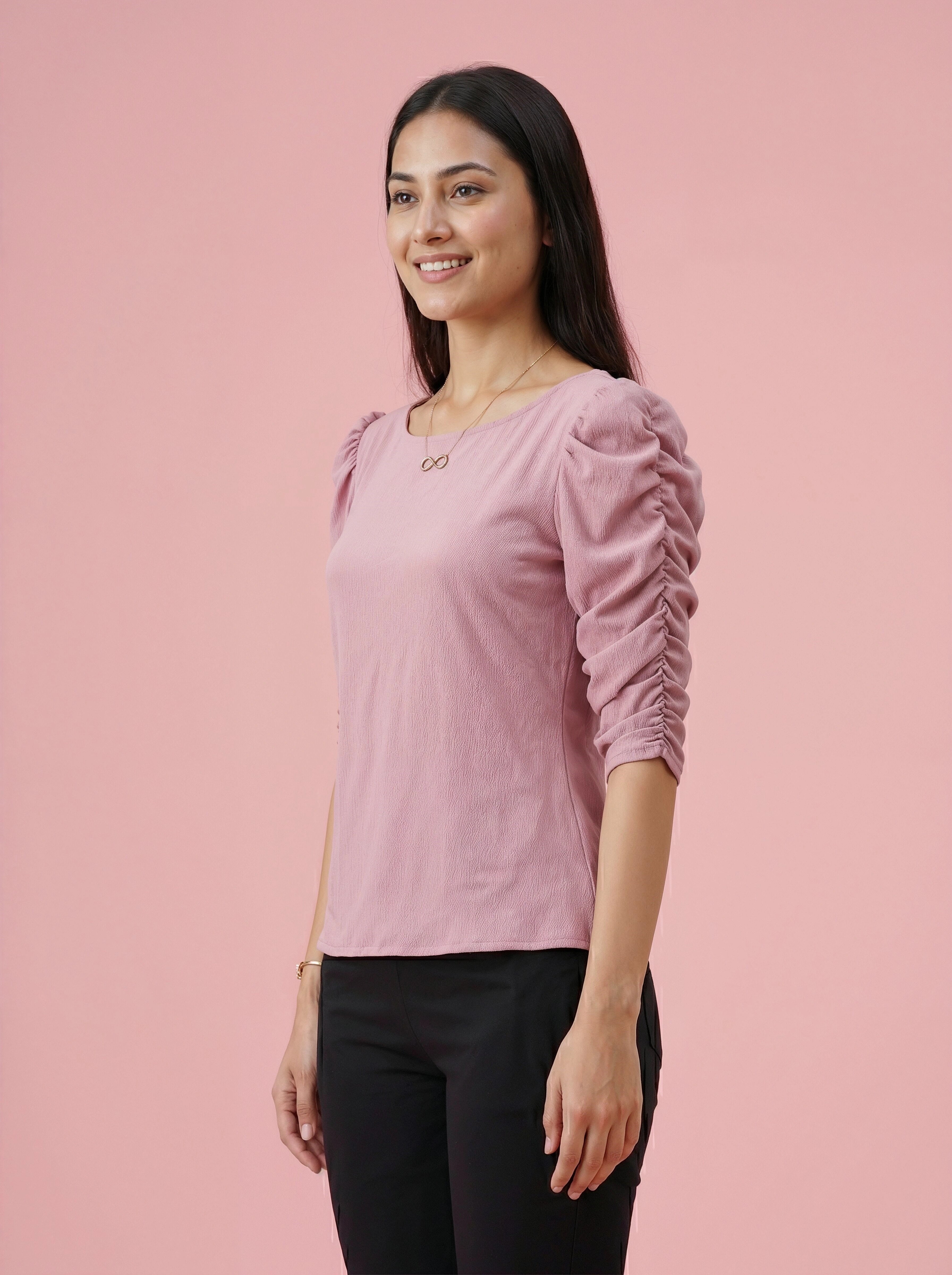 Woman wearing a pink blouse with ruffled sleeves against a pink background