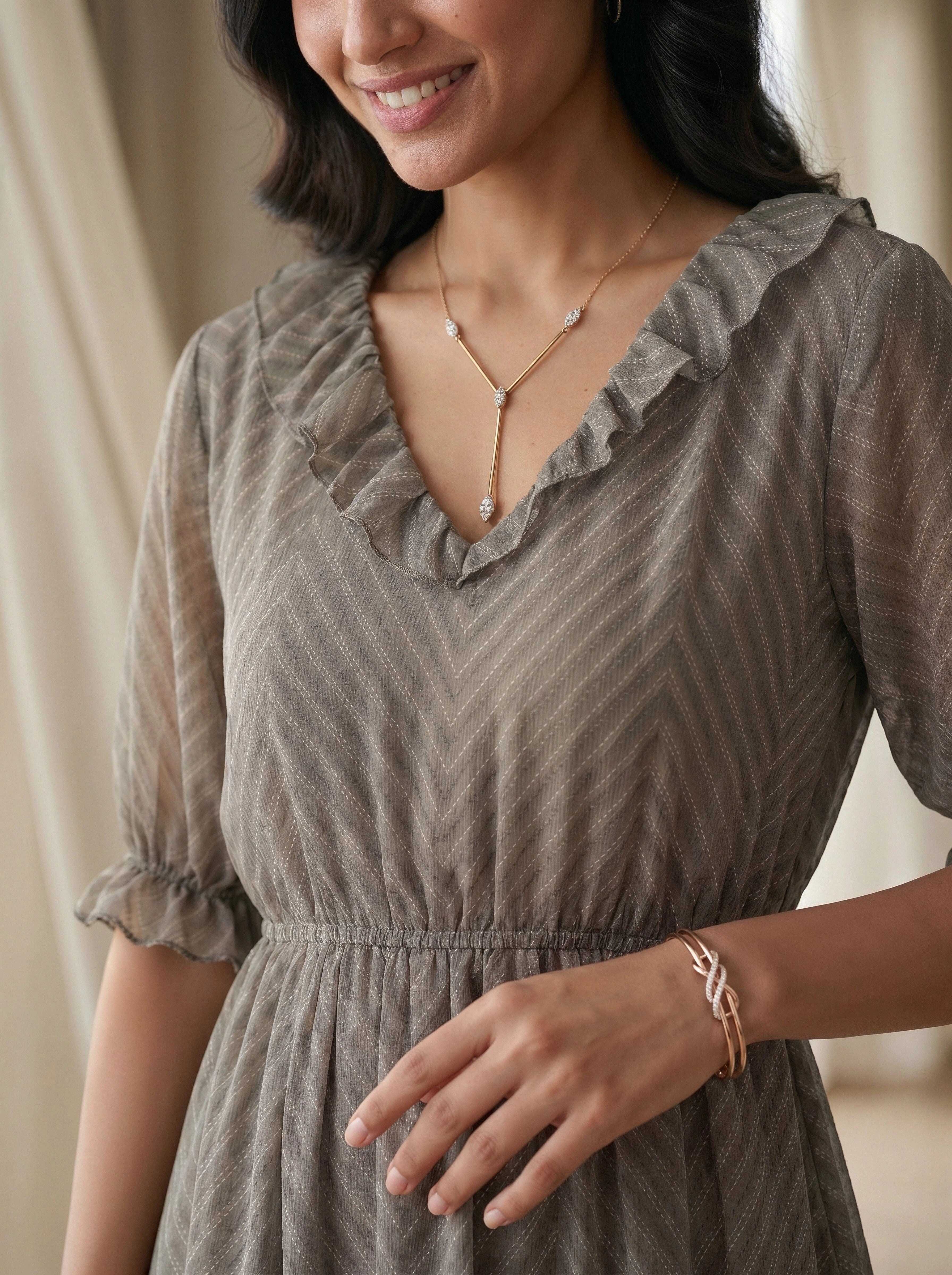 Woman wearing a gray dress with a subtle pattern, smiling and looking to the side.