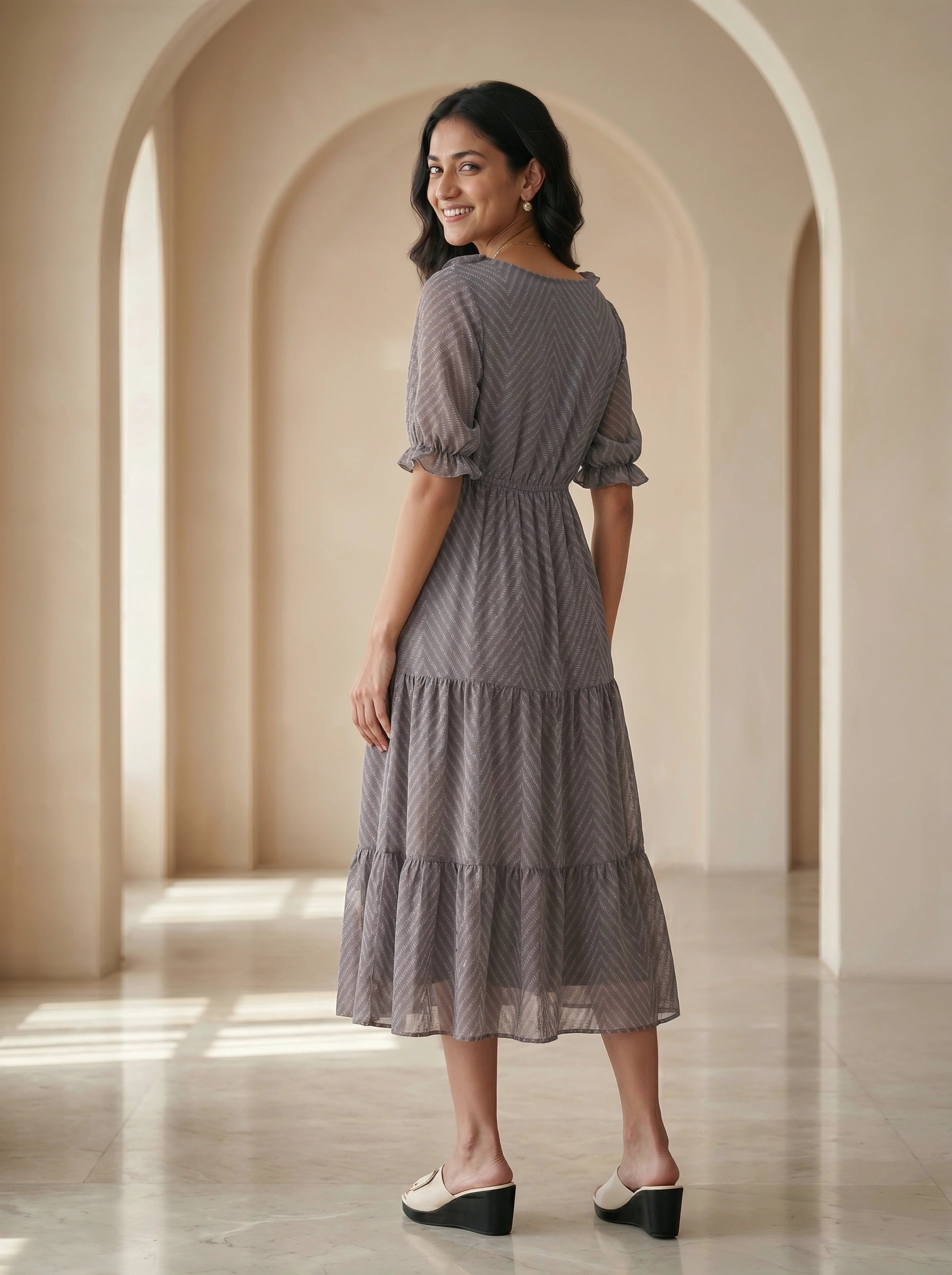 Woman in a gray dress standing in an archway with soft lighting