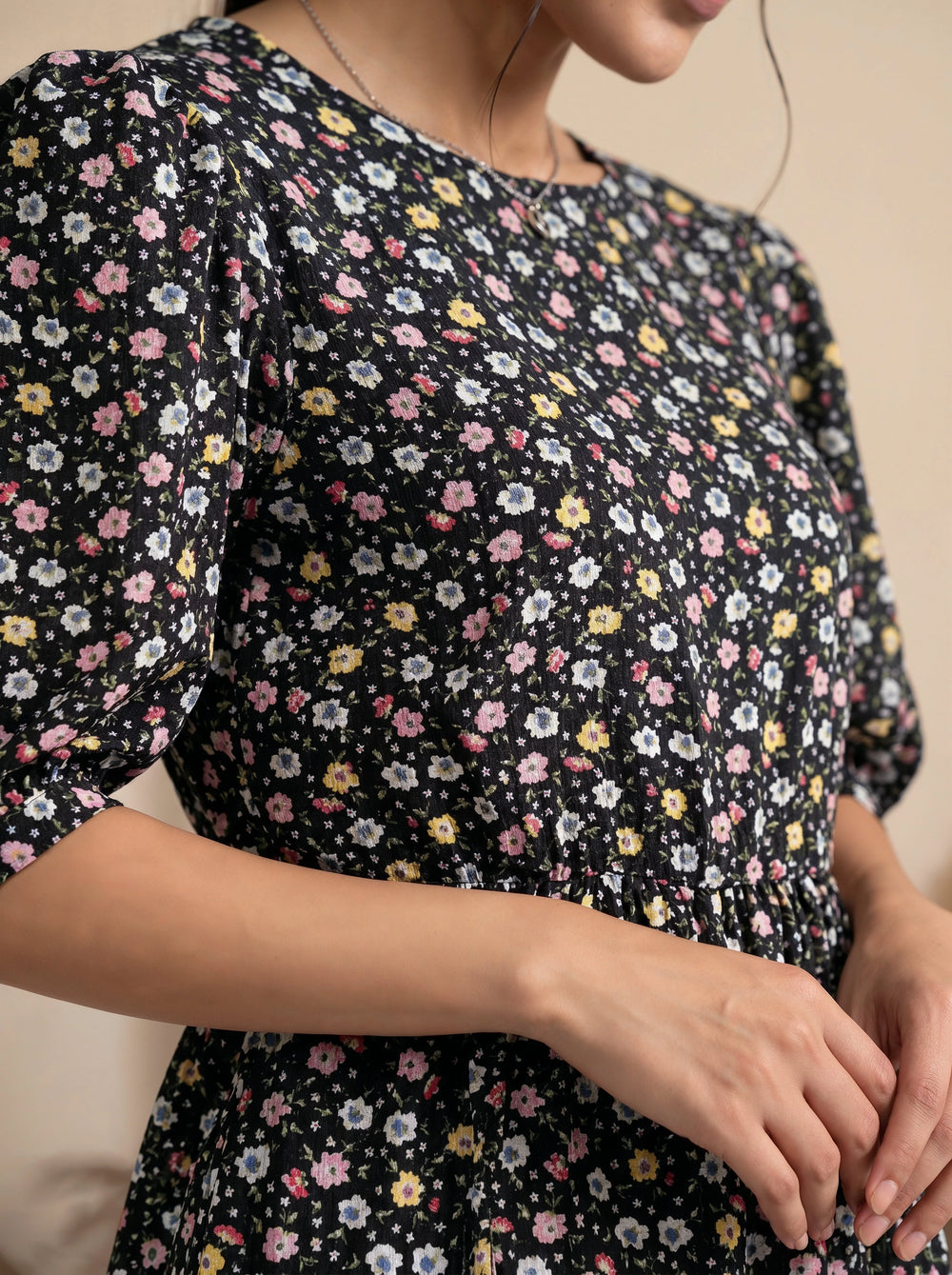 Woman wearing a black floral dress with a neutral background